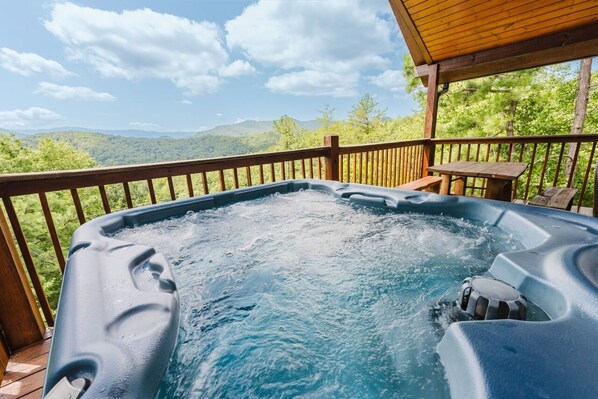 A hot tub on a wooden deck with a view of mountains.