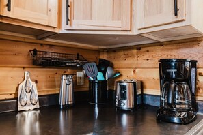 Una cocina con armarios de madera, cafetera, tostadora y un organizador de utensilios.