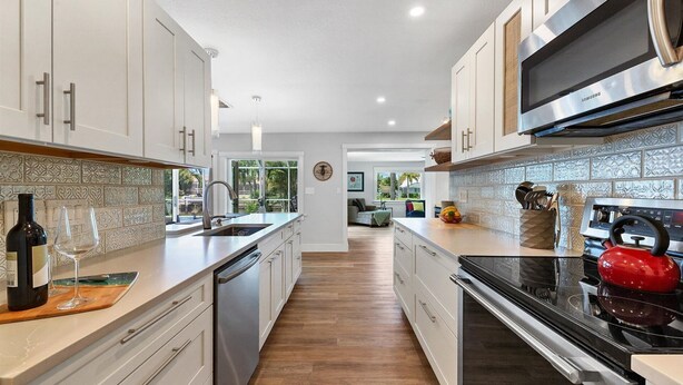 A modern kitchen with white cabinets, a stainless steel range hood, and a red kettle. - Beautiful Villa With First Class Amenities on Charlotte Harbor, Orlando Villa 5584 (Punta Gorda)