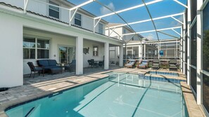 Área de piscina com um terraço envidraçado, mobiliário para área externa e uma piscina azul cristalina.