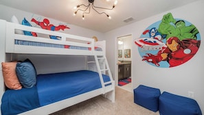 Een slaapkamer met een stapelbed en een muurschildering van Spider-Man en de Avengers, een ladder en blauwe kussens.