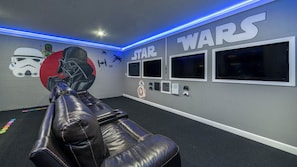 Een kamer in Star Wars thema, met muurschildering, een relax fauteuil en meerdere gaming monitoren.