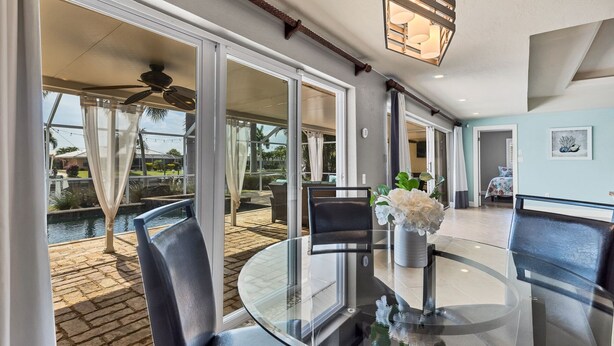 A spacious patio with a glass table and chairs, a ceiling fan, and a view of a swimming pool and greenery. - The Ultimate 5 Star Villa With Private Pool on Charlotte Harbor Area, Orlando Villa 5479 (Punta Gorda)