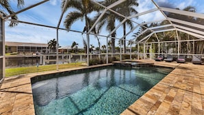 A pool with clear water, surrounded by a covered area with palm trees and lounge chairs. - The Ultimate 5 Star Villa With Private Pool on Charlotte Harbor Area, Orlando Villa 5479 (Punta Gorda)