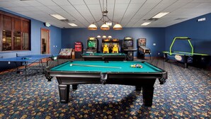 A pool table with billiard balls, a ping pong table, and arcade games in a room with blue walls and patterned carpet. - Charming Townhome Sleeps 8 5577 (Kissimmee)