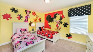 Habitación infantil con cama, mesita de noche y cómoda, decorada con motivos de Mickey Mouse y Minnie Mouse.