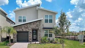 A modern two-story house with a stone facade, a garage, and a well-maintained lawn. - Modern Villa With Ocean Views 5588 (Kissimmee)