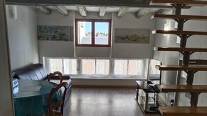A spacious room with a dining area, a staircase, and a large window providing natural light. - House on the Loire (Gien)
