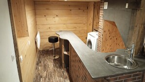 A compact kitchen with a sink, a washing machine, and a stool. - House on the Loire (Gien)