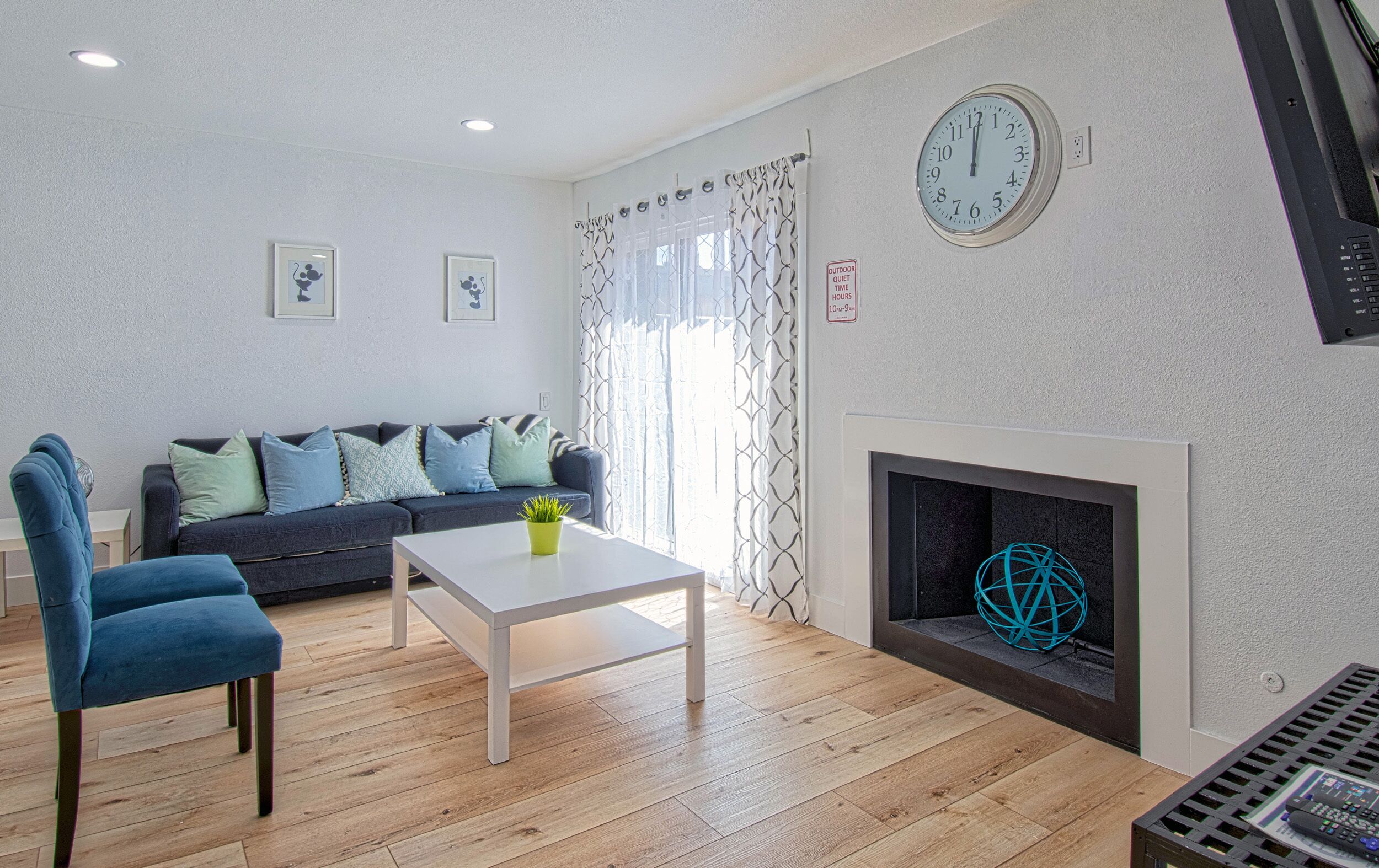 A living room with a sofa, a coffee table, a fireplace, and a clock on the wall.