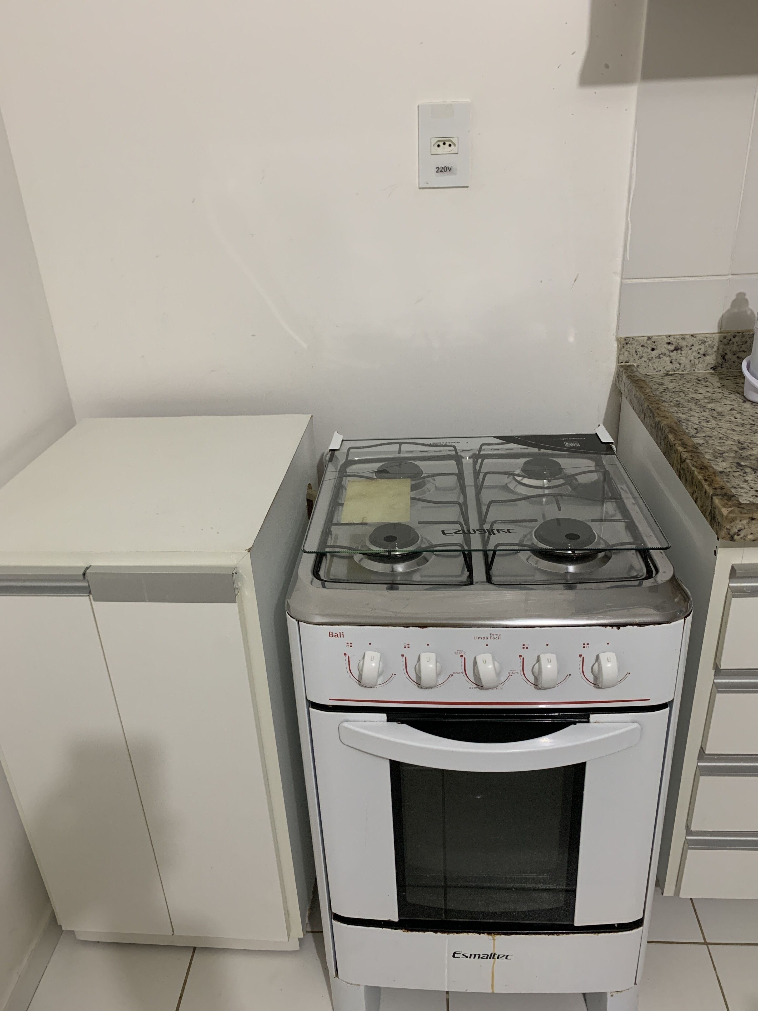 Una cucina compatta con fornello, forno e piccolo frigorifero bianchi.