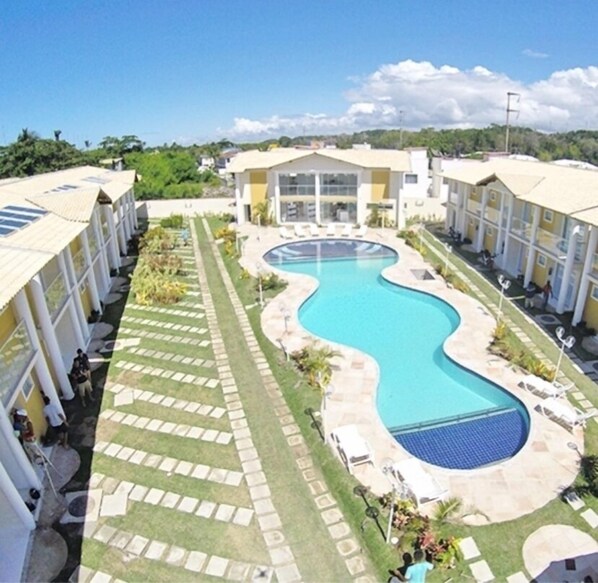 A hotel with a central swimming pool, multiple balconies, and a landscaped garden area.