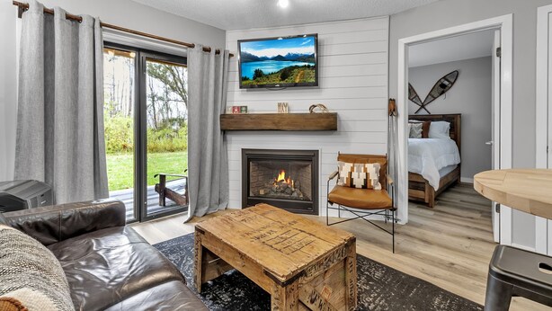 A modern living room with a fireplace, a television, and a cozy seating area. - Hillside Getaway Ski-In Ski-Out Retreat in Ellicottville, NY Sleeps 4 (Ellicottville)