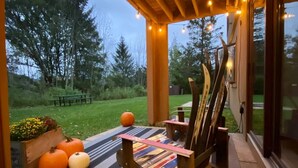 A wooden deck with string lights, a cushioned bench, and a view of the outdoors. - Hillside Getaway Ski-In Ski-Out Retreat in Ellicottville, NY Sleeps 4 (Ellicottville)