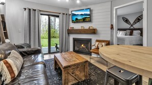 A modern living room with a fireplace, a television, and a dining area. - Hillside Getaway Ski-In Ski-Out Retreat in Ellicottville, NY Sleeps 4 (Ellicottville)