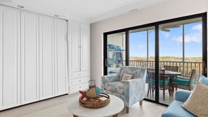 A spacious room with a large sliding glass door leading to an outdoor area, a round table with a decorative item, and a blue sofa.