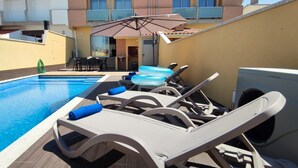 A swimming pool with lounge chairs and an umbrella.