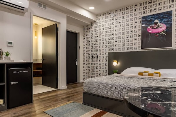 Un dormitorio con cama, televisor de pared, mesita de noche pequeña y armario.