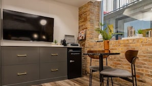 Una cocina moderna con televisor de pantalla plana, lavavajillas integrado y pared decorativa de ladrillo.