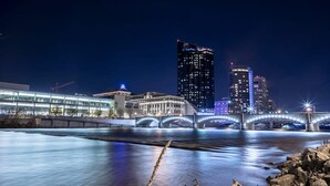 Una vista nocturna de la ciudad con un río, un puente y edificios modernos.