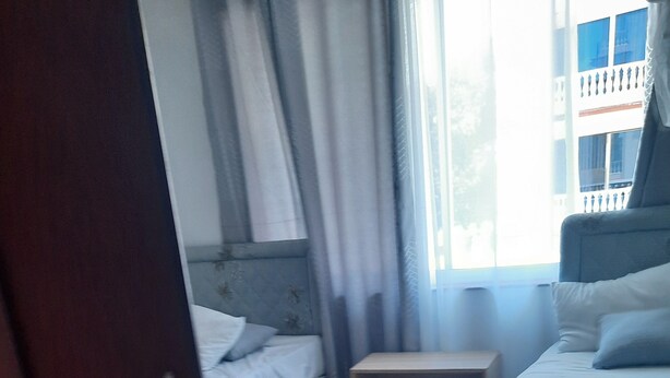 A hotel room with two beds, a small bedside table, and a window with curtains. - Best west $ (Kiambu County)