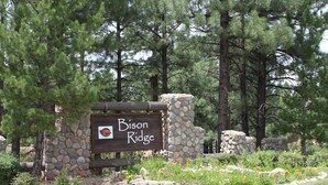 Un letrero de piedra con la inscripción "Bison Ridge", rodeado de follaje y árboles.