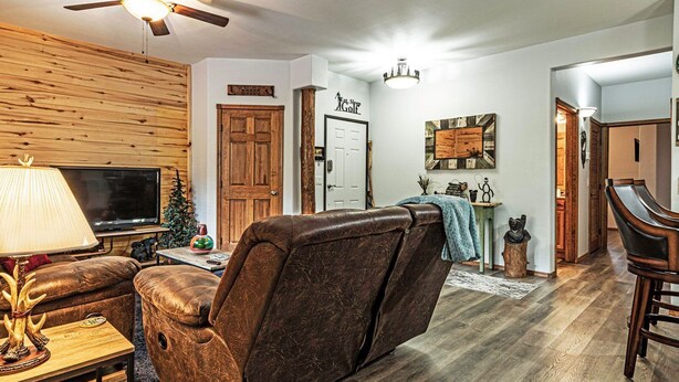 Una sala de estar con sofá de cuero, televisor y ventilador de techo.