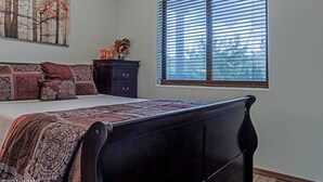 Un dormitorio con una cama, un aparador, una ventana con persianas y un cuadro en la pared.