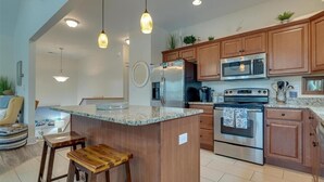Una cocina moderna con armarios de madera, electrodomésticos de acero inoxidable e iluminación colgante.