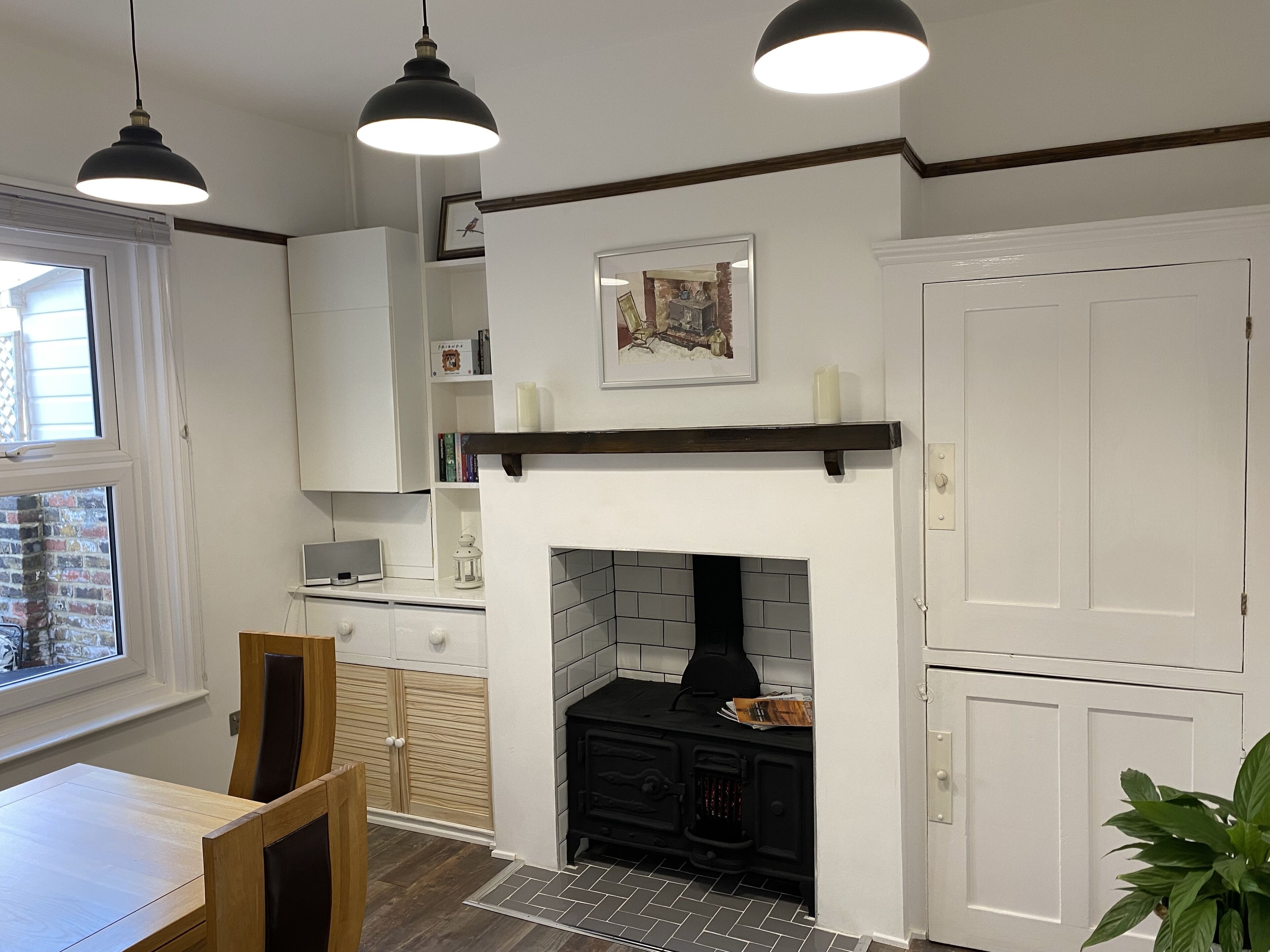 Une cuisine dotée d’une cheminée, de meubles en bois et de luminaires suspendus.