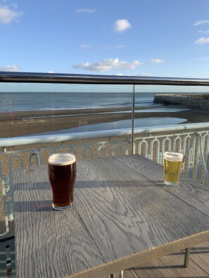 A wooden table with two glasses of beer, overlooking a beach and sea. - Cosy period house near the seafront (Ramsgate)