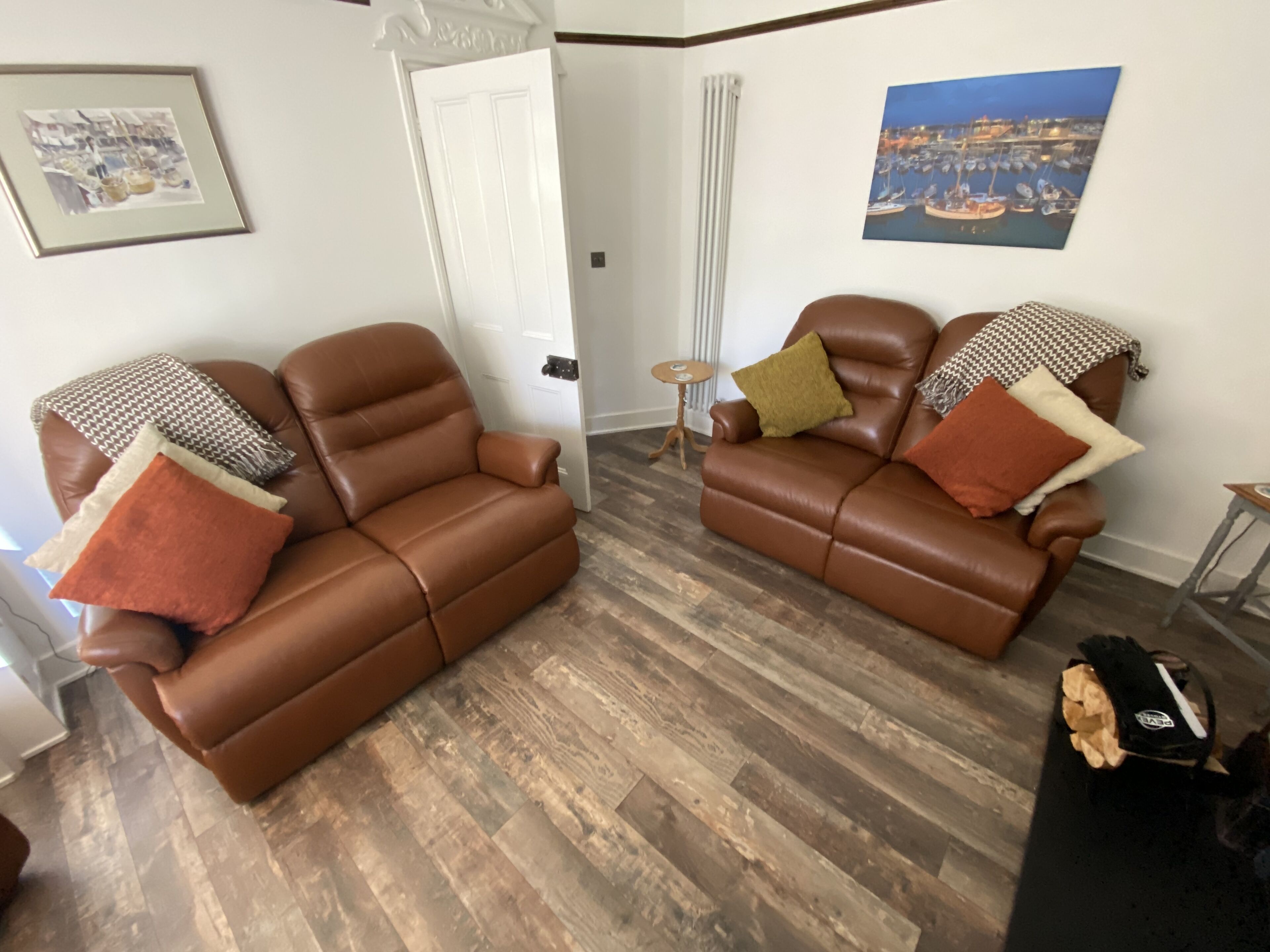 A living room with two brown leather sofas, a small round table, and a framed picture on the wall.