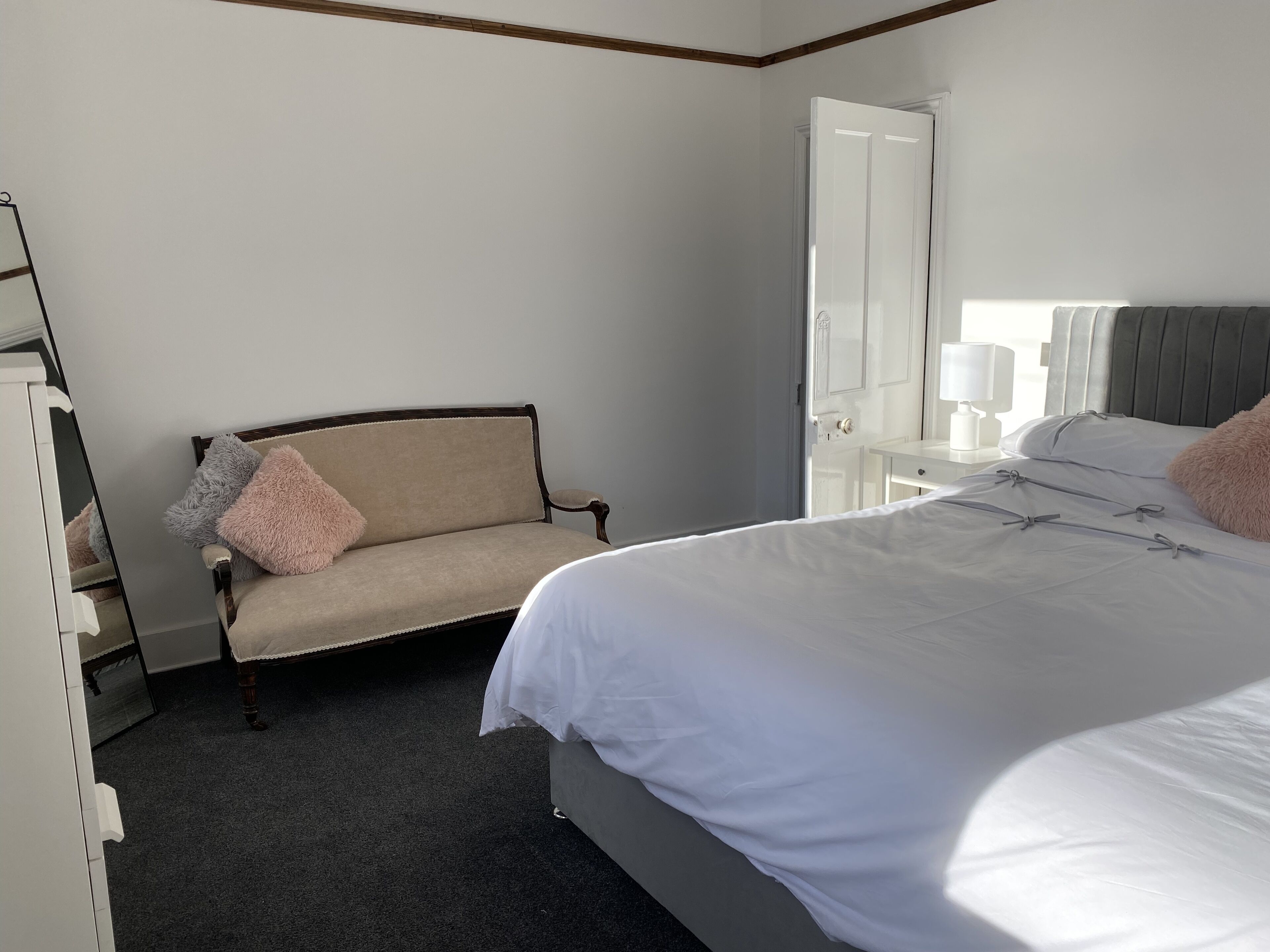 A bedroom with a bed, a chair, a dresser, and a mirror.