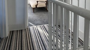 Ein Flur mit Teppichstreifen, der zu einem Schlafzimmer führt.