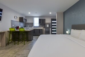 Ein kompaktes Hotelzimmer mit Küchenzeile, einem Bett und einem Essbereich.