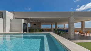 A modern indoor pool area with a clear view of the sky and distant buildings.