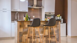 Een moderne keuken met een houten kookeiland, twee zwarte barkrukken, een inbouwoven en een magnetron.