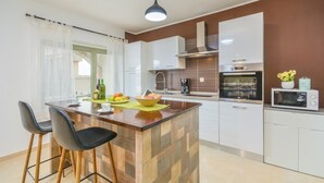 Een moderne keuken met een houten eiland, witte kastjes, een inbouwoven en een magnetron.