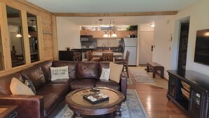 A cozy living room with a brown leather sofa, a wooden coffee table, and a TV on a wooden cabinet.