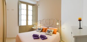 A neatly arranged bedroom with a bed, pillows, a bedside table, and a lamp.