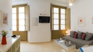 Ein modernes Wohnzimmer mit einer Couch, einem Couchtisch und einem an der Wand montierten Fernseher.