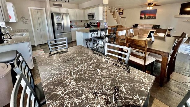 A spacious kitchen with a marble countertop, a dining area with a wooden table and chairs, and a staircase leading to another level. - Glendale Pool Heated Pet Friendly (Glendale)