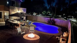 A backyard with a swimming pool, a fire pit, and outdoor furniture. - Glendale Pool Heated Pet Friendly (Glendale)