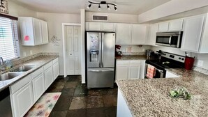 A modern kitchen with white cabinets, a stainless steel refrigerator, a microwave, and a granite countertop. - Glendale Pool Heated Pet Friendly (Glendale)