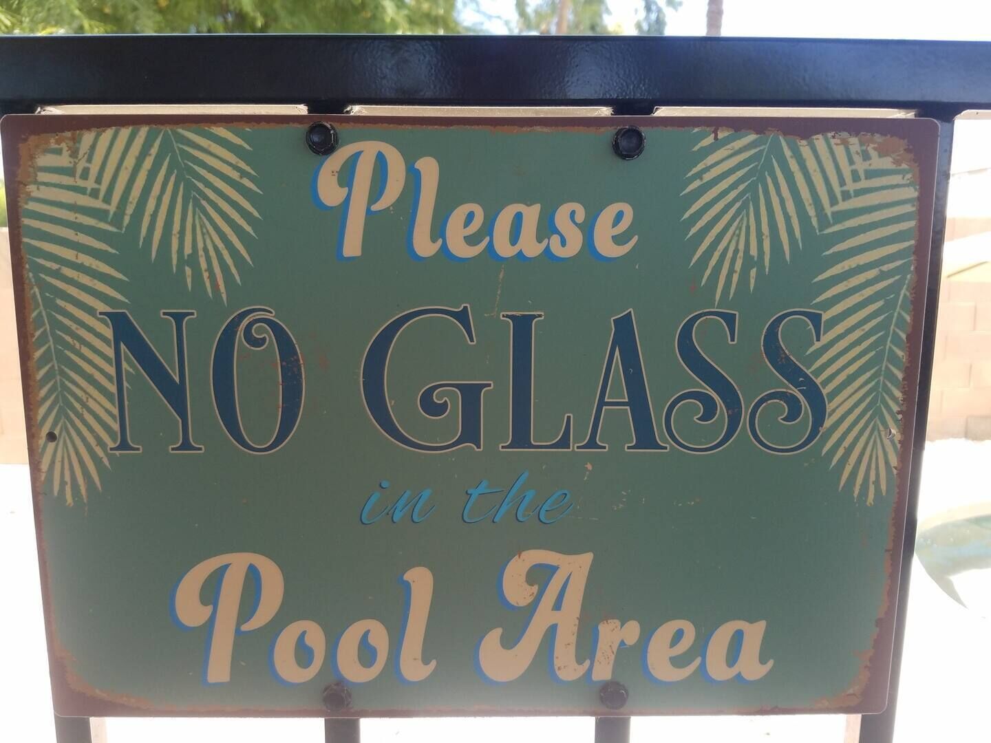 A sign with the text "Please NO GLASS in the Pool Area".