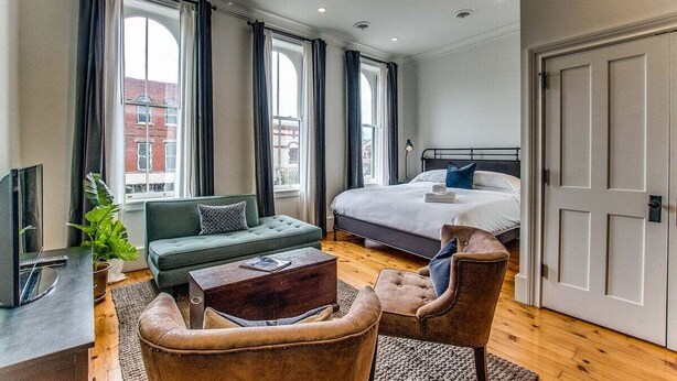 Una habitación de hotel moderna con una cama grande, un sofá, una mesita de centro y un televisor.