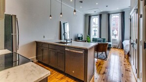 Una cocina moderna con una isla central, lavavajillas integrado e iluminación colgante.