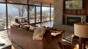 A modern living room with a large sofa, a fireplace, and a television. - Panoramic Views, pool and 2 hot tubs, pool table (Sedona)