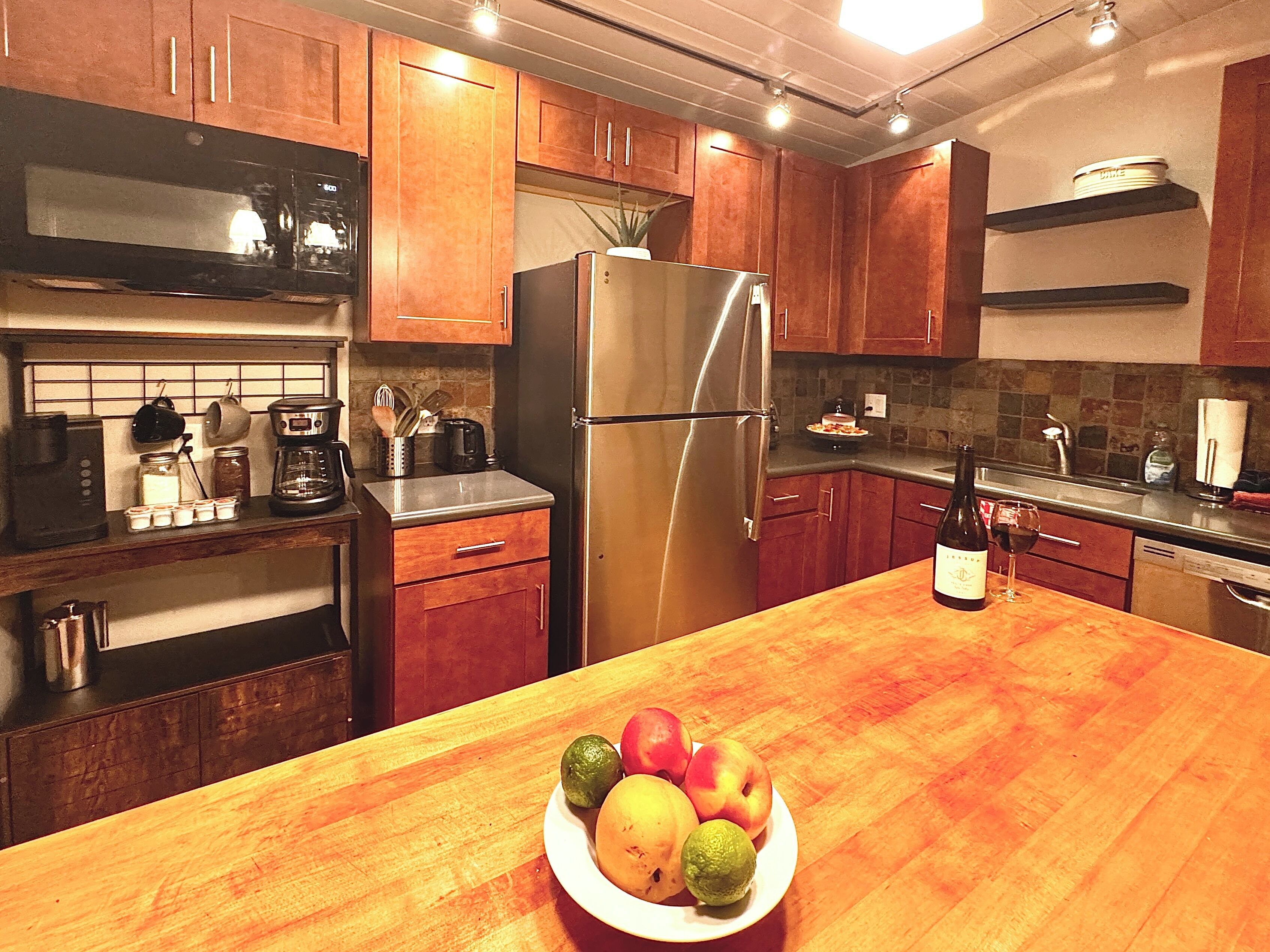 Een moderne keuken met houten kastjes, roestvrijstalen apparatuur en een centraal eiland met een fruitschaal.