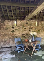 A rustic stone wall with a wooden table and two blue chairs.
